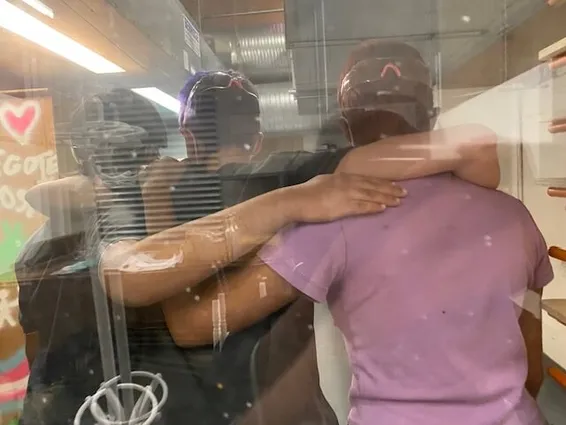 Three people with arms around each other through a window