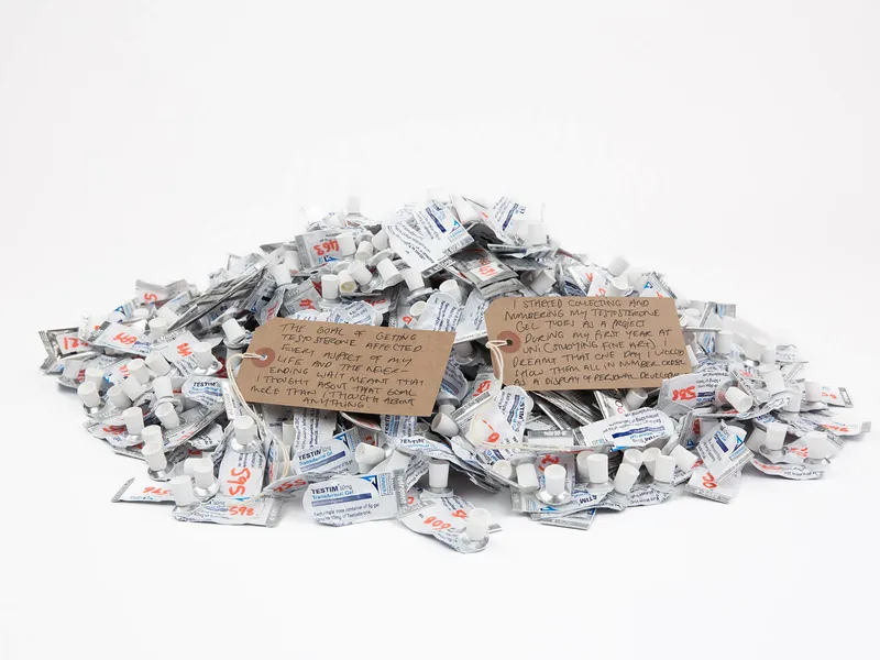 A huge pile of empty testosterone tubes with two luggage tags