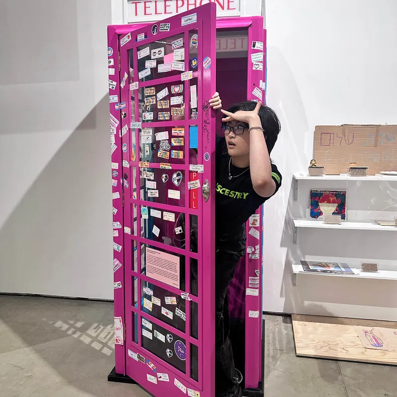 A person putting their head out of a pink telephone box